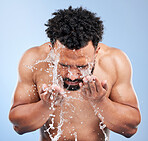 Black man, water and washing face for skincare, hygiene or grooming against a blue studio background. African male person, model and aqua splash for body hydration, shower or facial skin treatment