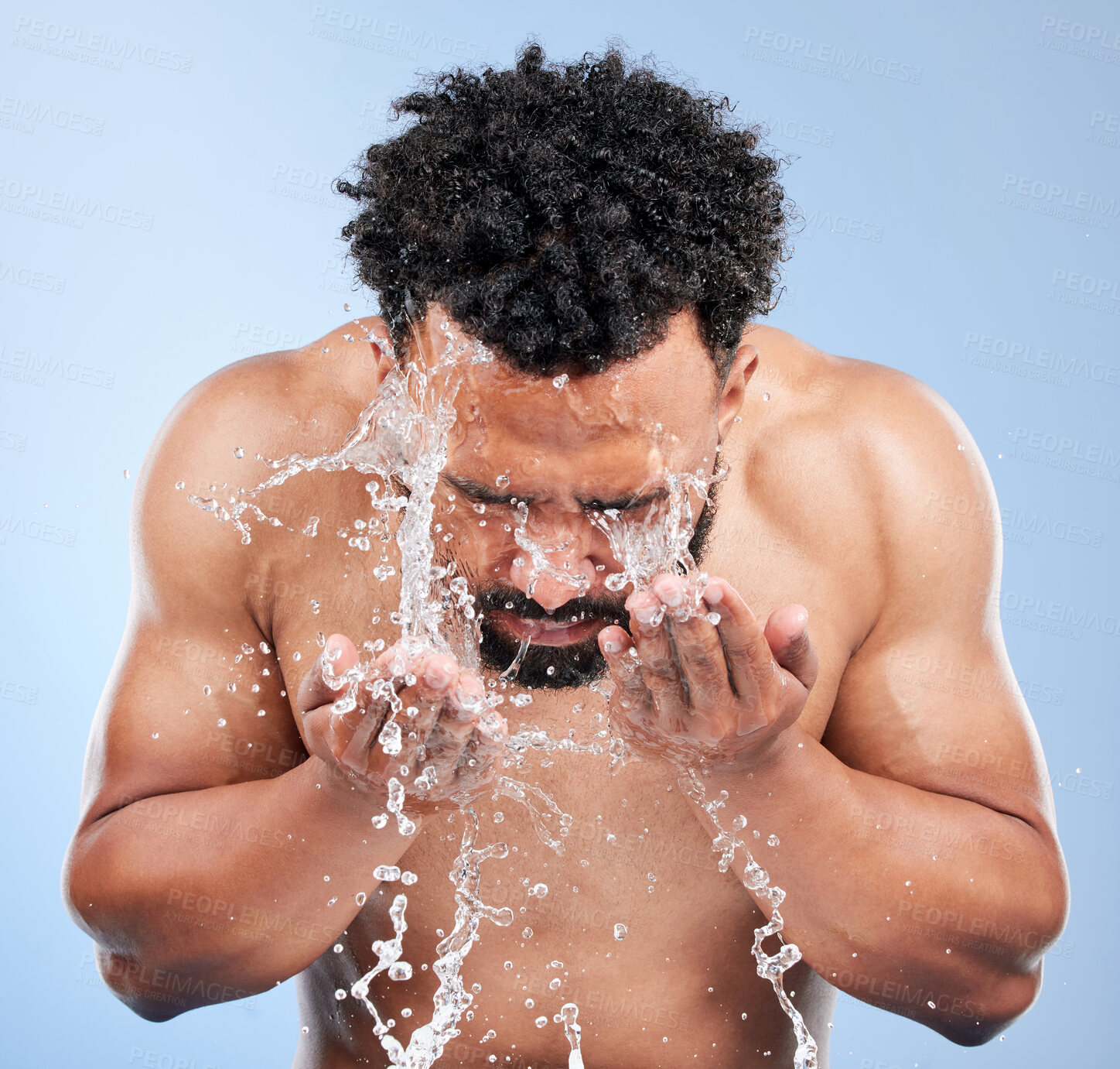 Buy stock photo Black man, water and washing face for skincare, hygiene or grooming against a blue studio background. African male person, model and aqua splash for body hydration, shower or facial skin treatment