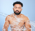 Black man, water splash and skincare for hygiene, cleaning or grooming against a blue studio background. Face of African male person, model and aqua for body hydration, shower or washing skin