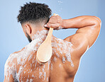 Shower, washing and man with brush and soap in studio for cleaning, hygiene and skincare on blue background. Dermatology, bathroom and person with foam and cosmetics for wellness, health or self care