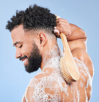 Shower, brush and man in studio for back cleaning, exfoliate or wellness on blue background. Soap, cosmetics and profile of happy model with body scrubber in a bathroom for hygiene, washing or care