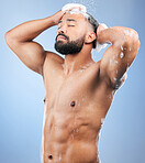 Shower, washing hair and man with foam in studio for cleaning, hygiene and skincare on blue background. Dermatology, bathroom and person with soap, shampoo and cosmetics for wellness and health