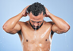 Shower, washing and man with water in studio for cleaning, hygiene and skincare on blue background. Dermatology, bathroom and person with splash, drops and cosmetics for wellness, health or self care