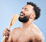 Brush, shower and man singing in studio for cleaning, wellness or morning routine on blue background. Bathroom, karaoke and male model having fun with body scrubber, cosmetics or luxury washing