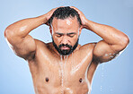 Shower, washing hair and man with water in studio for cleaning, hygiene and skincare on blue background. Dermatology, bathroom and person with drops or splash for wellness, grooming and self care