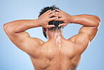 Man, shower back and muscle in studio with water, splash and hygiene with self car blue background. Person, guy and cleaning with hair, wellness and health for skin, natural and dermatology for body