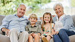 Smile, portrait and children with grandparents on a sofa in the living room of modern family home. Happy, love and young kids sitting with grandfather and grandmother on couch in the lounge at house.
