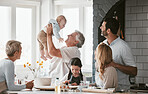 Family, kitchen and grandpa playing with baby having fun, bonding and relax together. Big family, support or care of grandfather carrying newborn with mother, father and girl child cooking in house