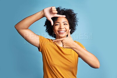 Buy stock photo Portrait, frame and woman with a smile, focus and confident girl against a blue studio background. Face, female person or model with hand gesture, framing and shape with profile picture and happiness