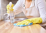 Woman, spray bottle and hands cleaning table in housekeeping, hygiene or disinfection with gloves in kitchen. Closeup of female person wiping surface, counter or furniture in bacteria or germ removal