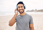 Smile, headphones and portrait of man on the beach running for race, marathon or competition training. Happy, fitness and young male athlete listen to music, radio or playlist for exercise by ocean.