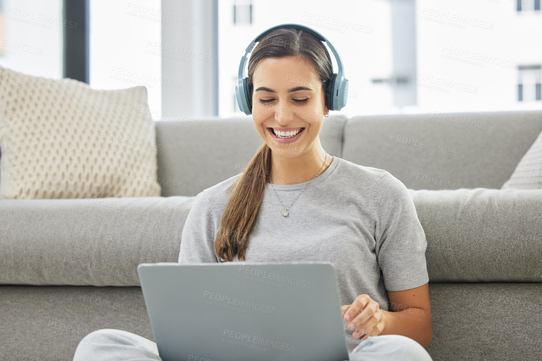 Buy stock photo Happy, headphones and laptop with woman online in home with remote work, music and living room with smile. Podcast, tech and internet with radio streaming and audio with computer by a sofa with job