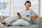 Sofa, headphones and phone with credit card and woman at home with purchase, music and smile. Online shopping, tech and internet with banking and audio with mobile by a sofa with digital buying