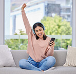 Woman, excited and phone with headphones for music on a home sofa with happiness and energy. Happy female person on a lounge couch with a smartphone for streaming or listen to audio, podcast or radio