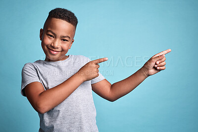 Buy stock photo Mockup space, idea and happy boy pointing in a studio with a solution, advertising and marketing. Portrait of happiness, smile and young african kid with a positive thought and with blue background.