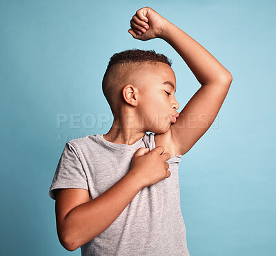 Buy stock photo Children, bicep and kiss with a boy bodybuilder in studio on a blue background for fitness, health or wellness. Sports, strong and kids with a young male child kissing his arm muscle during training