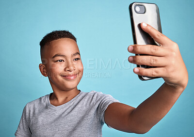 Buy stock photo Phone, selfie and boy child with happy smile for confident and carefree digital photograph fun. Cheerful male preteen smiling for smartphone camera picture with blue background for mock up.