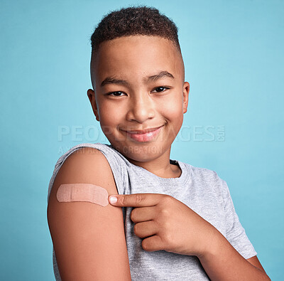 Buy stock photo Child black, band aid and happy kid with vaccine, in blue studio background and relax with smile or joyful. Portrait, boy and adhesive bandage with arm bruise, confident and vaccination for health.