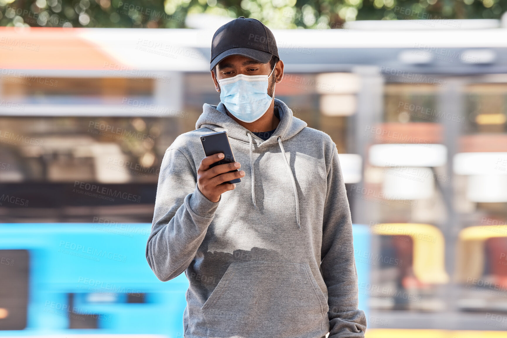 Buy stock photo Man in city with mask, phone and morning travel at bus stop, checking service schedule or social media. Public transport safety in covid, urban commute and person in street with smartphone connection