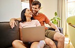 Couple browsing on an internet website with laptop while relaxing on sofa at home. Happy, in love and young people online shopping while bonding in living room. Partners streaming movie on technology
