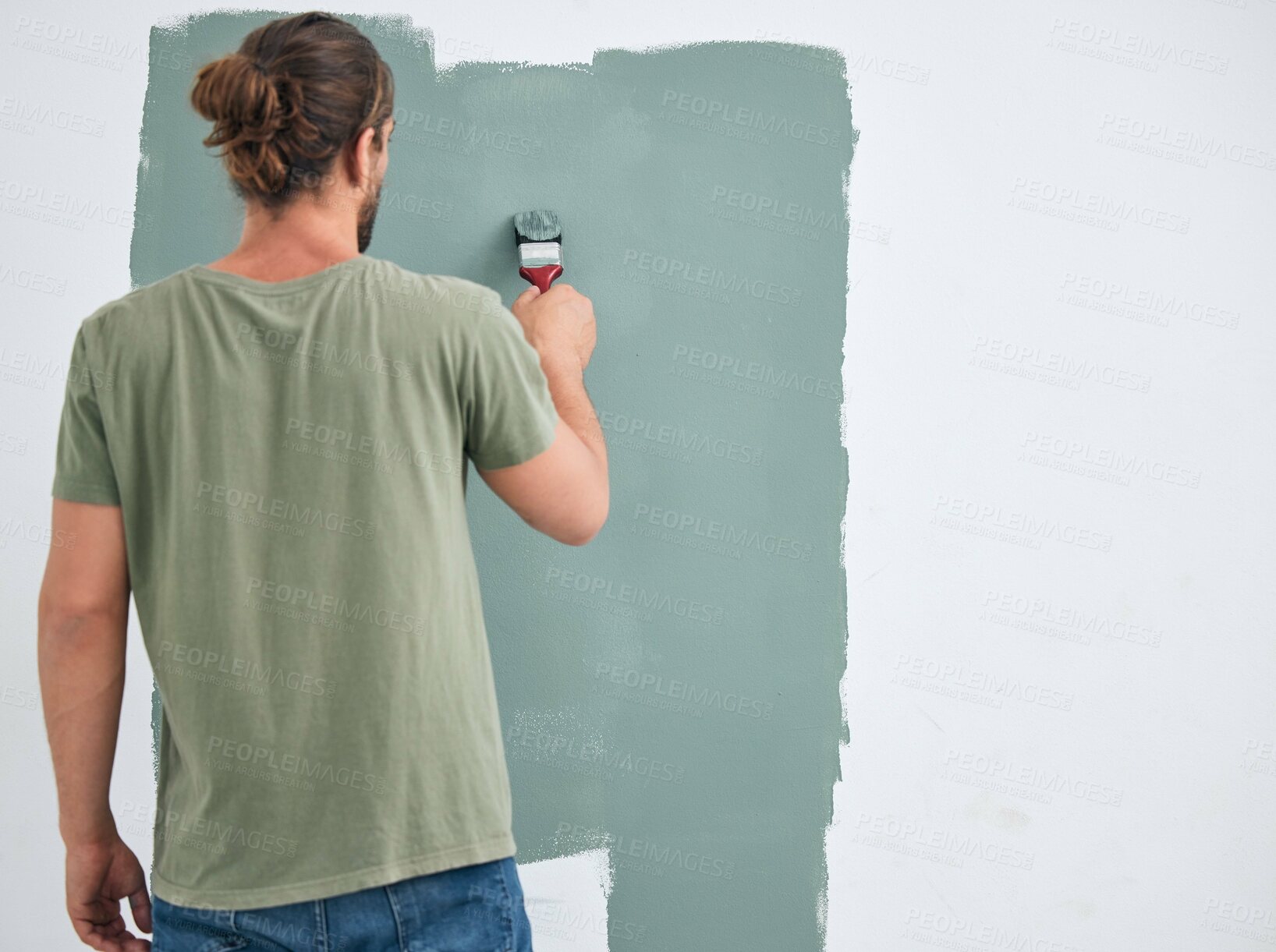 Buy stock photo Painting, brush and renovation with a man doing interior DIY in a room for improvement and remodel of home. Young man, decoration and work with green paint on a wall to maintenance in domestic house
