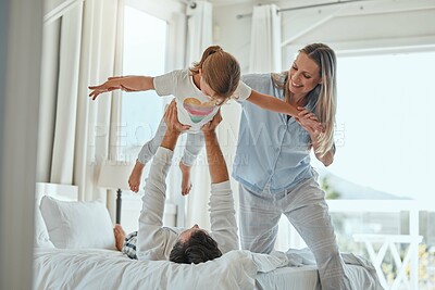 Buy stock photo Family, mother and father lifting girl, playing and bonding in home bedroom. Love, support and happy man and woman holding child up in air, enjoying quality time together and having fun in house.
