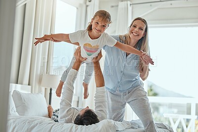 Buy stock photo Family, children and playful with a girl, mother and father having fun together in the bedroom of their home. Kids, flying and bonding with a man, woman and daughter playing on a bed in their house