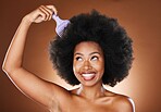 Beauty, hair care and black woman with afro comb in studio isolated on a brown background. Afro hair, wellness and happy female model with hair tool for hairstyle, salon treatment or healthy hair.
