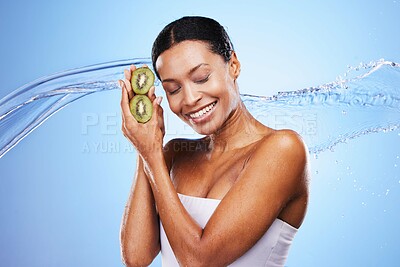 Buy stock photo Skincare, beauty and kiwi with a water splash and black woman with a smile on a blue studio background for hydration, self care and dermatology. Happy model with omega 3 and vitamin c for skin glow