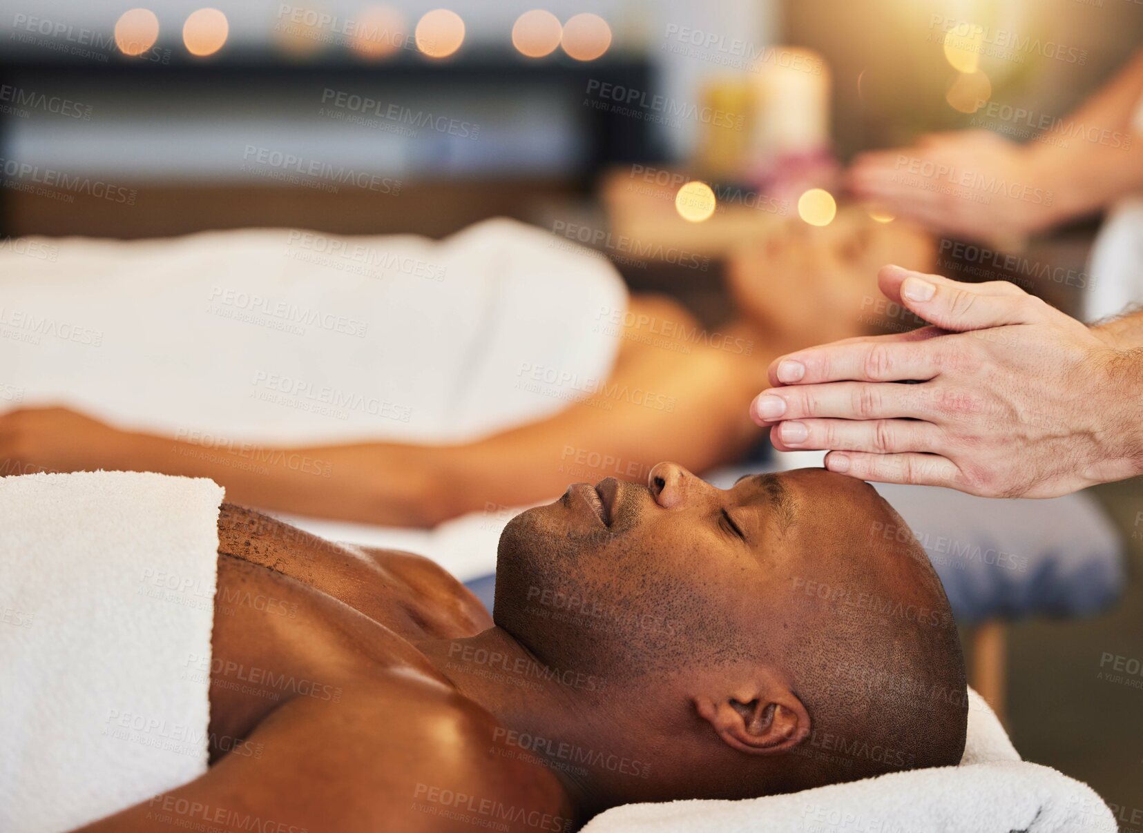 Buy stock photo Hands, massage and relax with a black man customer in a spa for physical therapy or rest in a resort. Luxury, wellness and zen with a male client lying on a bed for stress relief at a lodge