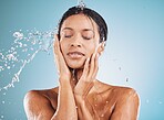 Water, cleaning and shower with a black woman in studio on a blue background for hygiene or hydration. Relax, skincare and wellness with an attractive young female washing her skin in the bathroom