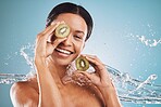 Skincare, water and portrait of woman with kiwi for natural, organic and healthy beauty products in studio. Dermatology, wellness and girl with fruit, water splash and cosmetics on blue background