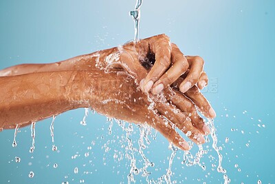 Buy stock photo Black woman, water splash or washing hands on blue background in studio for hygiene maintenance, healthcare or wellness. Zoom, wet model or cleaning fingers for bacteria security or virus risk safety