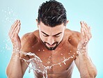 Skincare, water splash and man in a studio for a wellness, health and self care body routine. Cosmetics, hydration and male model with natural dermatology facial treatment isolated by blue background