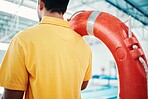 Lifeguard, man and swimming pool safety at indoor facility for training, swim and exercise. Pool, attendant and water sports worker watching for danger, protection or diving athletics, ready and safe