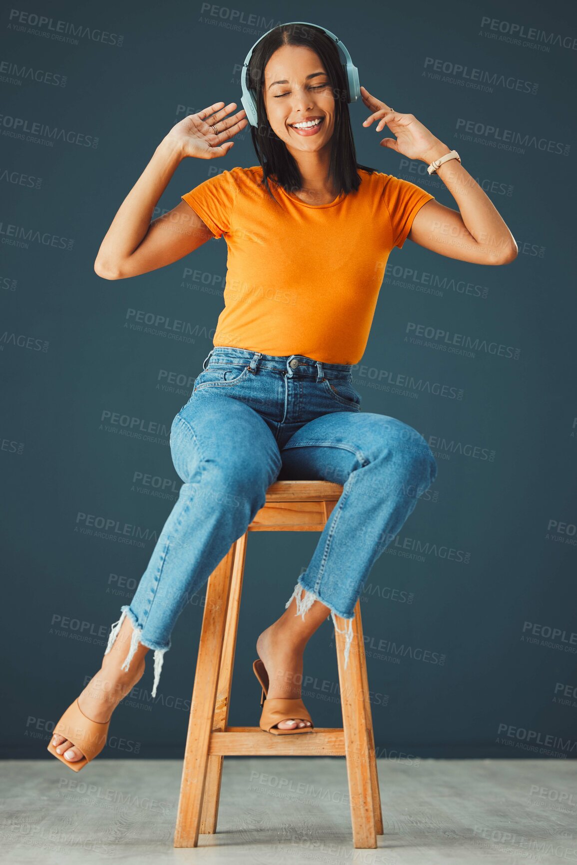 Buy stock photo Woman, headphones and listening to music while dancing and streaming online on a studio background. Happy gen z person with headset for podcast, radio or audio sound on chair to relax for freedom