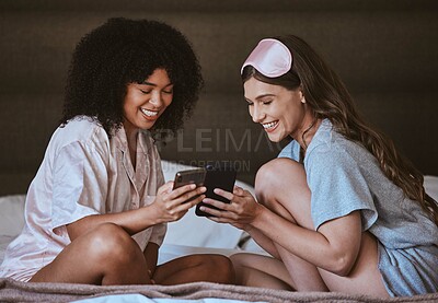 Buy stock photo Woman, friends and phone on bed with smile for social media, networking or funny meme in sleepover at home. Happy women smiling, laughing or relaxing with smartphone entertainment in the bedroom