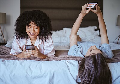 Buy stock photo Video call, phone and friends with women at sleepover for communication, internet and contact. Happy, relax and smile with girl lying in bedroom with technology, digital and social media together 