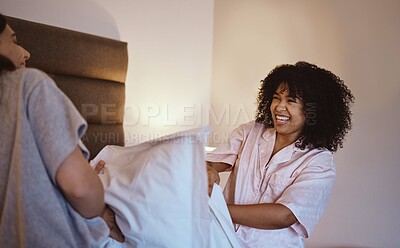 Buy stock photo Women, laughing or pillow fight in house, home or hotel bedroom in fun game, energy activity or sleepover challenge. Smile, happy or play fighting friends and linen product, bedding or bonding comedy