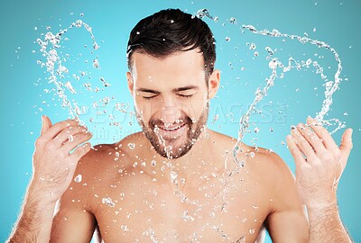 Buy stock photo Water, skincare and man with facial splash, smile and morning cleaning treatment isolated on blue background. Face, hygiene and male model grooming for health, wellness and clean skin care in studio.