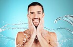 Water splash, skincare and portrait of man cleaning face, morning treatment isolated on blue background. Facial hygiene, male model and grooming for health, wellness and clean skin care in studio.