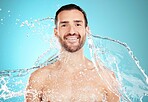 Water splash, skincare and portrait of man with smile on face and morning detox routine isolated on blue background. Hygiene, happy male model and grooming for health, wellness and beauty in studio.