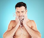 Water splash, skincare and man with hands on beard, morning cleaning treatment isolated on blue background. Facial hygiene, male model and grooming face for health, wellness and skin care in studio.