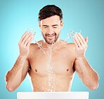 Water splash, sink and skincare of a man cleaning face for wellness, self care and dermatology. Liquid, model ad blue background in a studio with a young man with tattoo doing treatment for beauty