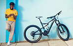 Phone, bicycle and black man on blue background in city for travelling on weekend, freedom and cycling. Urban transport, 5g network and male with smartphone for chat, social media and online message