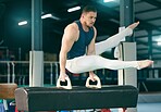 Gymnastics, practice and man training for a competition, performance and exercise in a gym. Focus, fitness and athlete gymnast doing a movement with balance, strength and artistic with flexibility