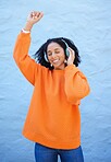 Black woman, headphones and music for dance by wall background on urban adventure, relax or freedom. African gen z girl, streaming audio or quality sound on radio, web or internet for dancing in city