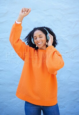 Buy stock photo Black woman, headphones and music for dance by wall background on urban adventure, relax or freedom. African gen z girl, streaming audio or quality sound on radio, web or internet for dancing in city