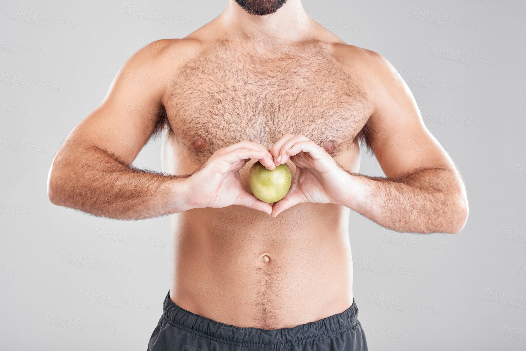 Buy stock photo Man, fitness and heart hands with apple in studio isolated on a gray background. Food, wellness and male model with love hand gesture, fruits for nutrition or healthy diet, vitamin c or minerals.