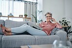 Senior woman, sofa and phone call in home living room with smile, relax and newspaper for happy portrait. Retirement, smartphone communication and elderly lady on lounge couch for smile, chat or talk